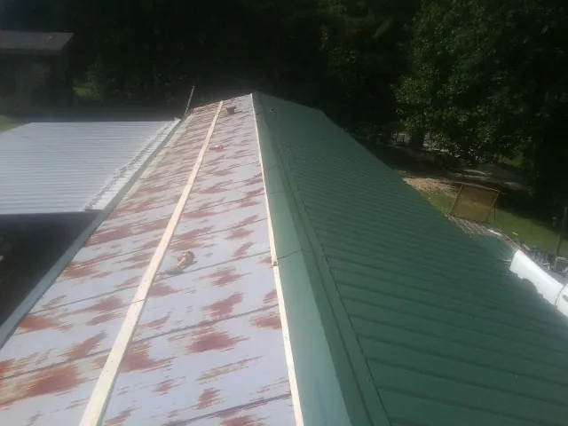 Old rusted panels beside newly installed green metal roofing — Wind Damage Roof Repair by Roofing Brothers in Zephyrhills