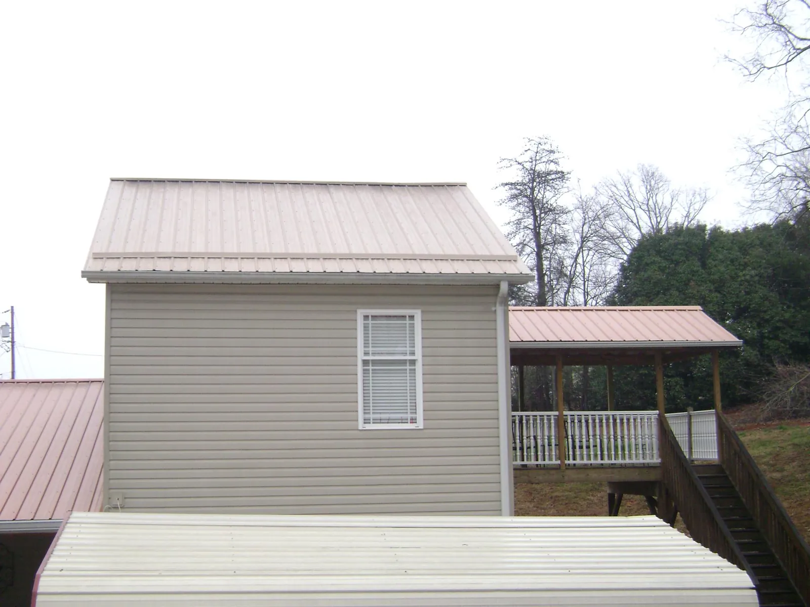 Tan metal roofs on a two story addition and attached porch, from a Roof Replacement job in Zephyrhills