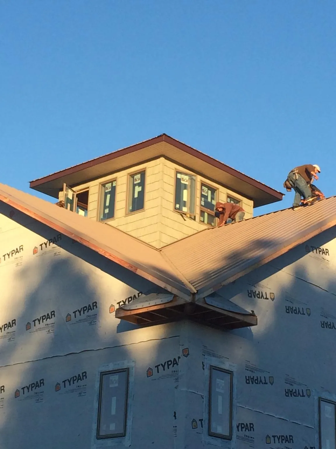 Roofers working around a rooftop cupola on a new metal roof at sunset — Roof Waterproofing in Zephyrhills by Roofing Brothers